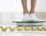 Legs standing on a scale with a measuring tape in the foreground